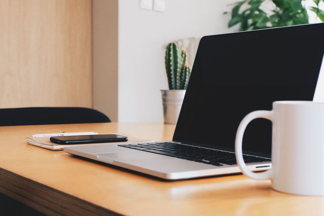 Uma mesa de escritório com café, celular e notebook. Foto: StockSnap/Pixabay.